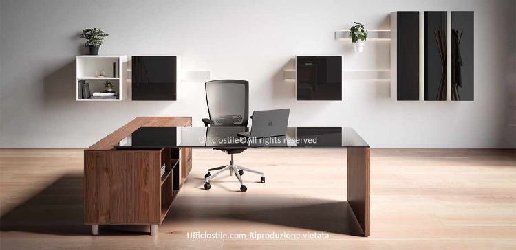 Scrivania direzionale Ufficiostile® con piano in vetro temperato extrachiaro retroverniciato nero, acidato, spessore 10 mm, bordi lucidi e ghiere in acciaio, struttura con fianco ribassato in melaminico Classe E1, abbinata a mobile di servizio portante da 180 x 58 x 69 cm con tre cassetti a serratura simultanea, tre vani a giorno e fondale integrale; contenitori a parete non compresi nel prezzo.