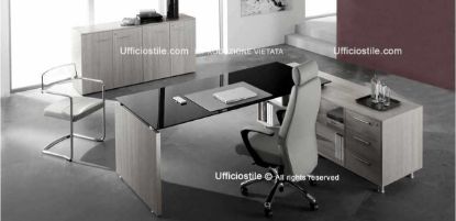 Postazione ufficio direzionale in pronta consegna con scrivania da 200 x 90 cm con piano in vetro retroverniciato, mobile di servizio collegato con ripiano laterale a giorno con schiena, ripiano centrale aperto e tre cassetti con serratura, libreria bassa a quattro ante con top e fianchi di finitura, realizzata in conglomerato ligneo rivestito in melaminico classe E1.