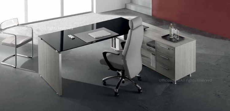 Scrivania direzionale con piano in vetro temperato retroverniciato da 180 x 90 cm, mobile di servizio collegato con tre cassetti con serratura e due ripiani a giorno, ingombro complessivo 200 x 180 cm, realizzata con materiali in conglomerato ligneo rivestito in melaminico classe E1 a bassa emissione di formaldeide.