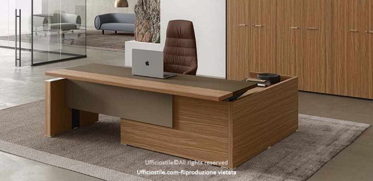 Composizione direzionale con scrivania dotata di piano elevabile e modesty panel in melaminico cappuccino o nocciola, mobile di servizio portante con ripiano interno, anta scorrevole soft-closing e serratura, realizzata in conglomerato ligneo spessore 38 mm con ingombro complessivo 180 x 214 x 75–141 cm.