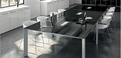 Tavolo riunioni rettangolare da 480 x 160 cm composto da 3 moduli indipendenti con piani in vetro temprato extra-chiaro spessore 10 mm, retrolaccato nero con superficie acidata, bordi perimetrali lavorati a filo lucido, 3 top access con coperchio a ribalta e gambe terminali in estruso di alluminio a forma trapezoidale.