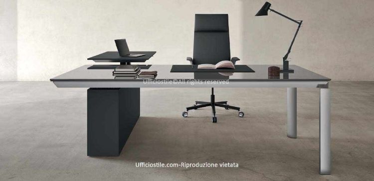Scrivania direzionale da 200 x 200 cm con piano principale in vetro temperato retroverniciato spessore 12 mm, bordo filo lucido, gambe in alluminio estruso brillantato sezione 80 x 80 mm e penisola meeting laterale regolabile in altezza con colonne motorizzate da 67 a 130 cm e piano laccato opaco.