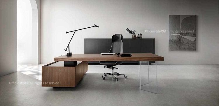 Scrivania direzionale da 180 cm con piano in legno, gamba in legno spessore 70 mm, gambe in vetro trasparente extrachiaro per effetto sospeso e mobile strutturale bifacciale da 200 x 75 cm con ante, cassettiera a 2 cassetti, vano tecnico, top access per passaggio cavi e predisposizione per prese integrate o tecnologia wireless.