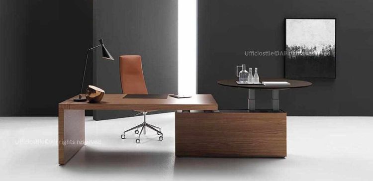 Scrivania direzionale con piano in legno da 180 cm, gamba spessore 70 mm e muretto portante con piano tondo da 120 cm regolabile elettricamente in altezza tramite sistema telescopico e pulsantiera sottopiano, con escursione fino a 130 cm per lavoro seduto o in piedi.