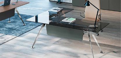 Scrivania direzionale angolare in vetro fumè con piano scrivania da 180 x 90 cm e allungo da 100 x 60 cm, piani in vetro temprato spessore 12 mm con bordi piatti a filo lucido, struttura in lamiera d’acciaio con basi circolari antiscivolo e gonna frontale in melaminico laccato grigio verdastro.