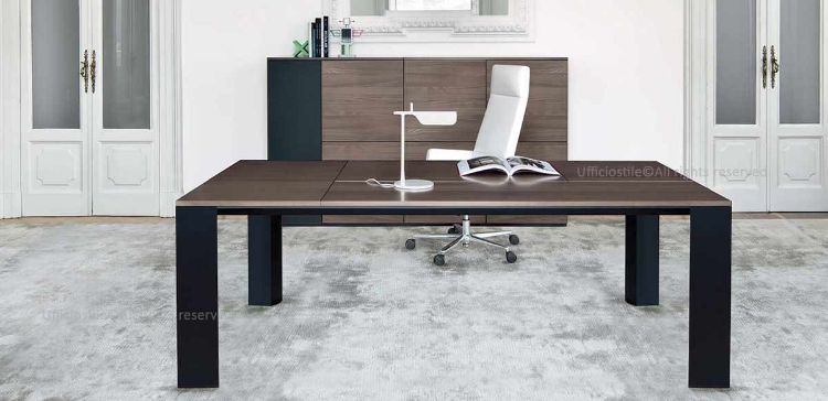 Scrivania direzionale Ono da 200 x 100 cm con top scorrevole, formella centrale con escursione di 10 cm per accesso al cablaggio nella vasca metallica, gamba in profilo estruso di alluminio a forma trapezoidale e composizione modulare madia da 220 x 46 x 123 cm con ante in melaminico e apertura push-pull.