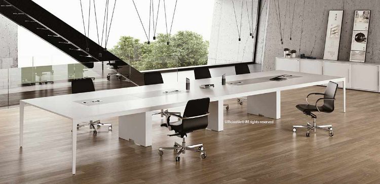 Tavolo riunioni modulare da 640 x 160 cm in melaminico bianco con inserti centrali laccati opachi, composto da quattro tavoli da 160 cm ciascuno, con struttura formata da due gambe laterali e tre gambe intermedie a muretto, adatto a ospitare circa venti persone e predisposto per elettrificazione opzionale tramite scatole di cablaggio.