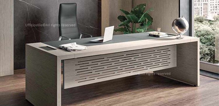 Scrivania direzionale impiallacciata da 204 x 100 cm con inserto in cuoietto, realizzata in pannelli MDF spessore 18 mm impiallacciati legno, lati longitudinali lavorati folding con fasce da 50 mm, inserto rivestito in cuoietto spessore 1,3 mm con cuciture decorative in tinta e gonna di cortesia impiallacciata con fresate passanti e verniciatura trasparente opaco a poro semiaperto.