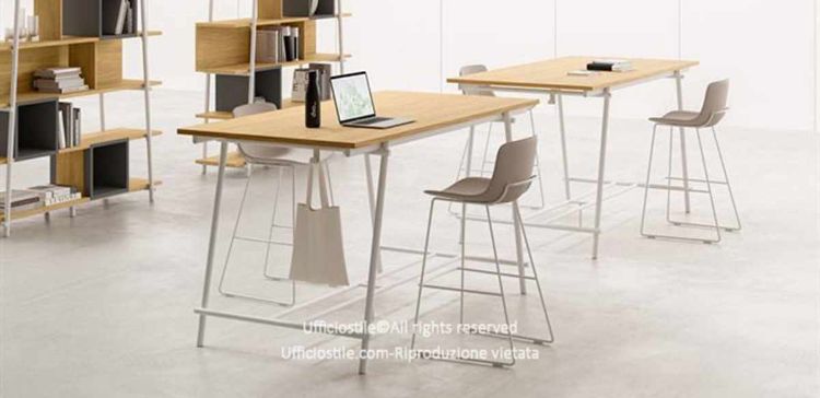 Tavolo alto h.107 da 180 x 100 cm con piano in melaminico rovere naturale spessore 25 mm, gambe in metallo verniciato bianco e gancio portaborse integrato, realizzato con pannelli in conglomerato ligneo rivestiti in melaminico e certificazioni FSC®, GREENGUARD® e CARB Phase 2.
