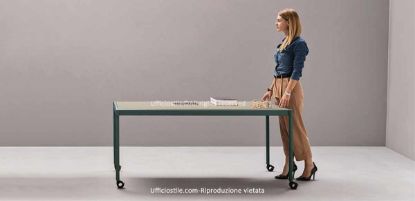 Tavolo plug-&-play su ruote per ufficio, meeting, formazione e catering corporate, con piano ultra-slim in melaminico laccato opaco, telaio perimetrale in alluminio, gambe tool-free, ruote pivotanti frenanti e componenti riciclabili.