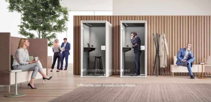Ambiente ufficio moderno con phone booth acustiche per telefonate e videocall riservate, complete di piano d’appoggio, presa elettrica e illuminazione integrata, affiancate da sedute imbottite ad alto schienale e panche basse con tavolini per aree attesa, relax e coworking, in uno spazio luminoso con finiture in legno chiaro e vegetazione decorativa.