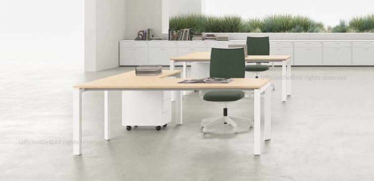 Scrivania da 180 x 180 cm con allungo, piani in conglomerato ligneo spessore 18 mm rivestiti in melaminico in diverse finiture, bordi ABS da 2 mm, gambe metalliche a forma di U rovesciata con traverso rettangolare e montanti triangolari, abbinata a cassettiera metallica su ruote a tre cassetti con serratura centralizzata, sistema antiribaltamento e due ruote con freno.