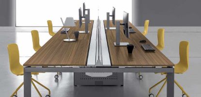 Scrivania bench a 6 posti composta da 3 bench con binario centrale attrezzabile, cavità interna per fissaggio di supporti in nylon o zama, sportelli apribili con cerniere in zama per accesso al piano e ispezione dei cablaggi, sistema push-pull integrato, schermi frontali e carter per le due gambe centrali con funzione passacavi.