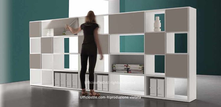 Libreria componibile per ufficio con ante a ribalta, struttura in conglomerato ligneo con rivestimento melaminico bianco, fianchi e ripiani da 38 mm, ante in diverse finiture melaminiche, bordi perimetrali in ABS e piedini livellatori regolabili dall’interno.