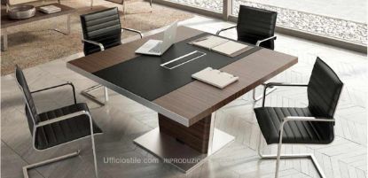 Tavolo riunioni quadrato da 141 x 140 cm con piano in legno impiallacciato e inserto in cuoio rigenerato, vaschetta raccogli cavi con coperchio basculante in alluminio estruso verniciato o brillantato rivestito superiormente in cuoio, spazzolini passacavi, piantana centrale in lamiera di acciaio decapata rivestita in acciaio inox spazzolato e pannelli esterni in MDF impiallacciato removibili per la discesa dei cavi elettrici.