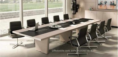 Tavolo riunioni da 421 x 140 cm con piano in legno impiallacciato e inserto in cuoio rigenerato, tre fori con vaschette raccogli cavi, coperchi basculanti in alluminio estruso verniciato o brillantato rivestiti superiormente in cuoio, spazzolini passacavi, gambe con telai in acciaio profilato spazzolato cromo e pannelli esterni in MDF impiallacciato removibili per la discesa dei cavi elettrici.