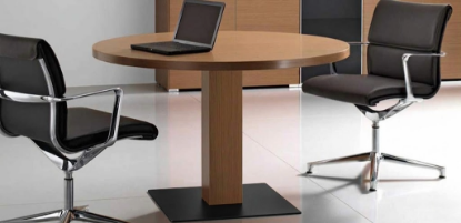 Tavolo riunioni tondo in legno con piano spessore 39 mm, base a pianta a sezione quadrata e piastra cromata, disponibile nelle finiture Wengè o Noce americano, ideale per sale riunioni, uffici direzionali e ambienti conference professionali.