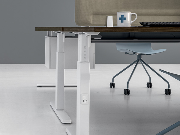 Dettaglio scrivanie regolabili sit-stand con piani soft-touch e gestione cavi integrata