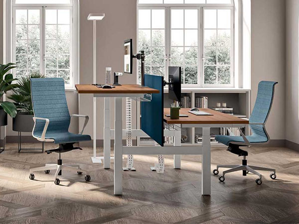 Persona che alterna lavoro seduto e in piedi su scrivania sit stand